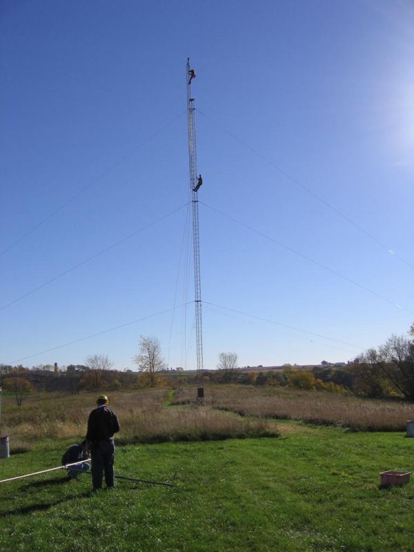 TOWER: Paul WØAIH on the Gin Pole with Chris KC9DGP below. GROUND: (l-r) Scott KA9FOX and Eric KB9TKF prepare 2m antenna for fin